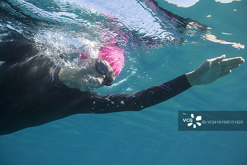 年轻女人在水晶般清澈的太浩湖自由泳，水下特写，晨光倒影图片素材