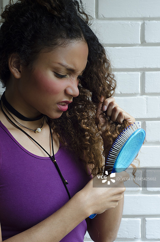 女人用发刷梳理头发，发型糟糕图片素材