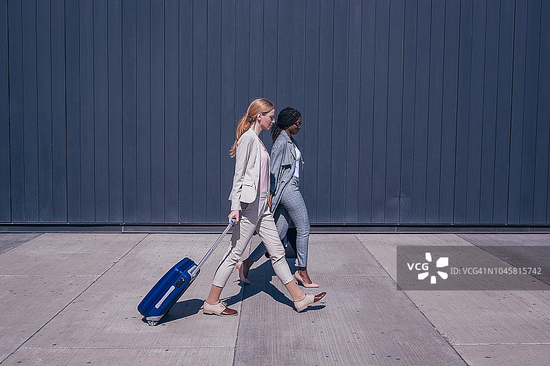 两个女商人急匆匆地从机场出来交谈图片素材