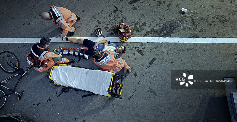 急救人员在事故现场将受伤的男自行车手抬上担架图片素材