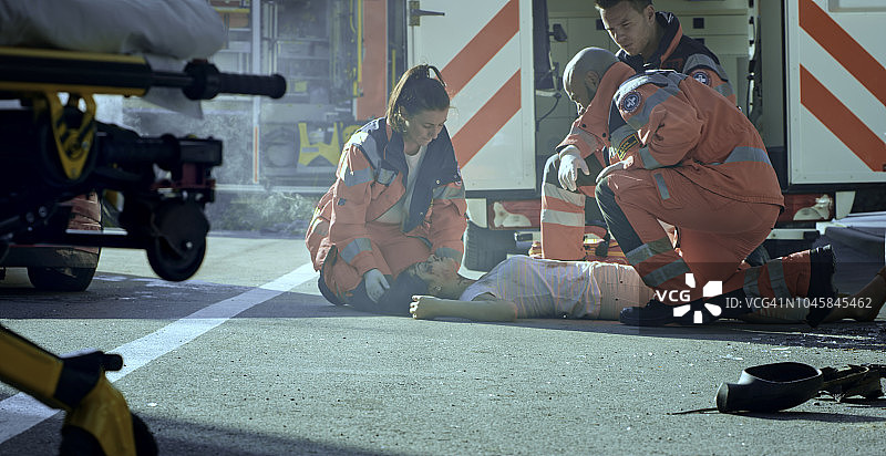 急救团队在车祸现场检查躺在地上的车祸受害者的生命体征图片素材