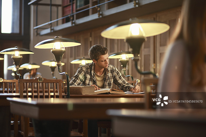 年轻男人在公共图书馆读书图片素材