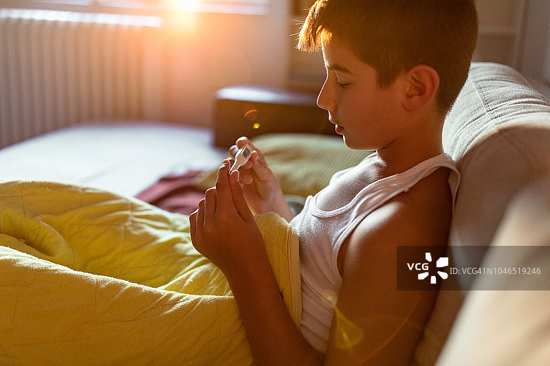 在床上量体温的男孩图片素材