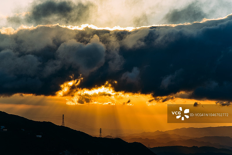 霞光穿过山上的戏剧性云层图片素材