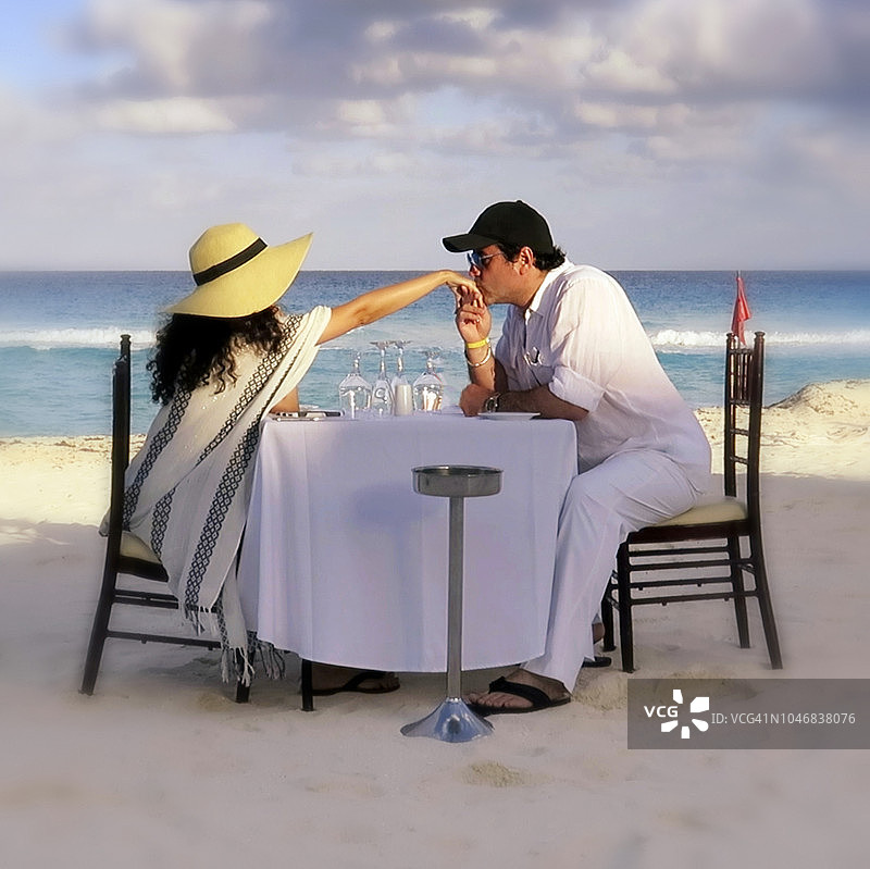 蜜月夫妇在海滩上共进晚餐。图片素材