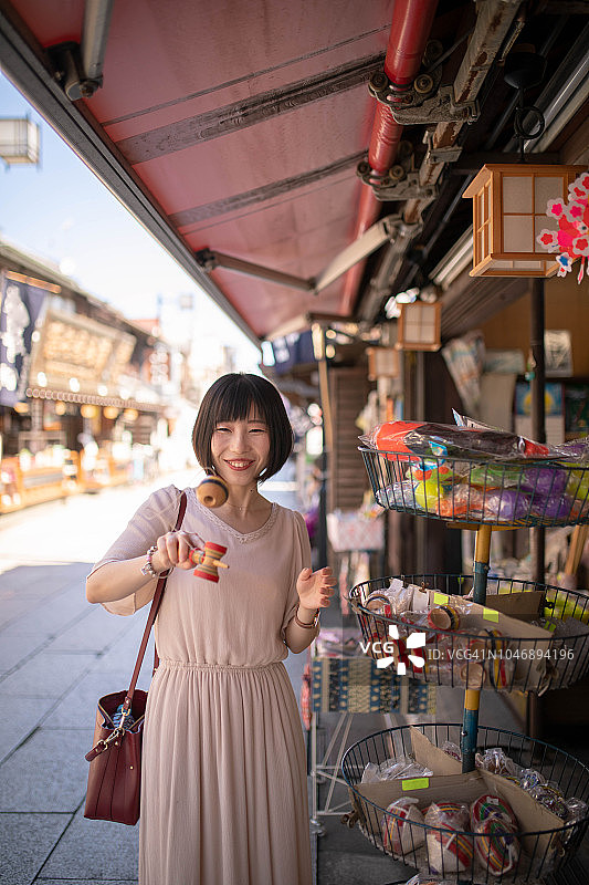 亚洲游客在日本传统商店尝试剑玉图片素材