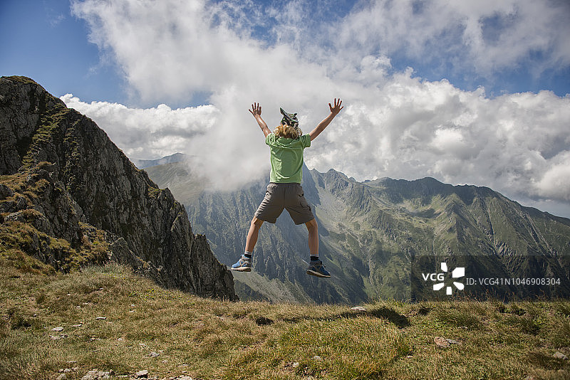 在罗马尼亚法格拉什山脉，小男孩跳跃着走向达拉峰图片素材