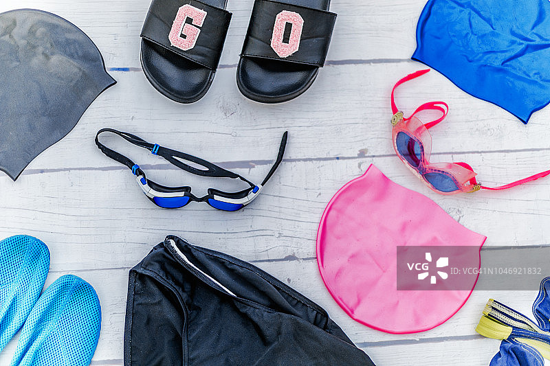 女士游泳配件：泳池安全眼镜、帽子、白色泳衣木质背景图片素材