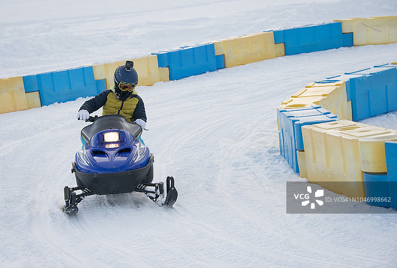 冬季在奥地利塞尔法斯-菲斯-拉迪斯滑雪胜地乘坐雪地摩托的小男孩图片素材