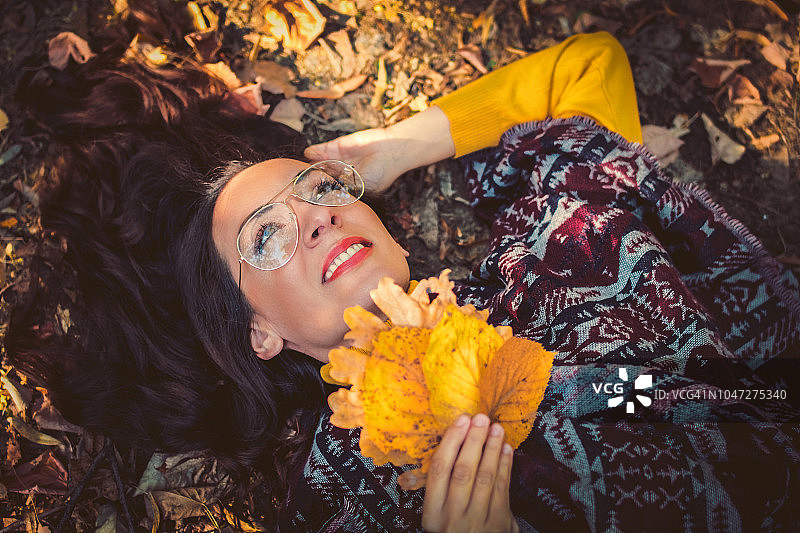 秋季人像：女子躺在彩色落叶上图片素材