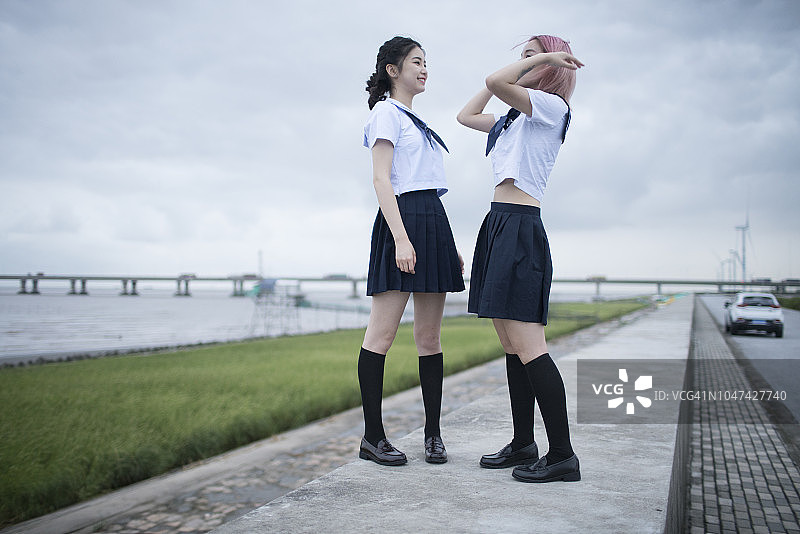 两名身穿校服的亚洲日本女学生站在防波堤上图片素材