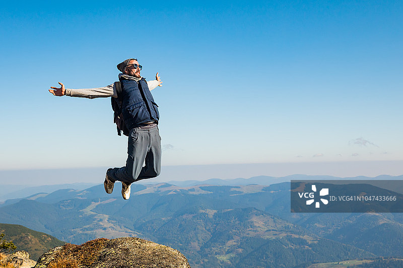 青年男子在山顶上对着天空跳跃图片素材