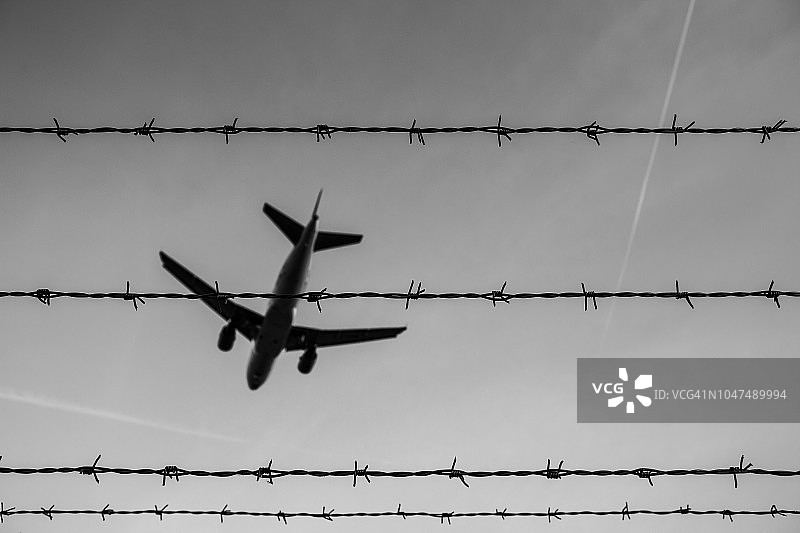 勃兰登堡舍内费尔德机场上空的带刺铁丝网和客机图片素材