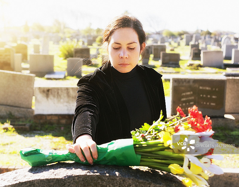 身穿黑色衣服在墓碑上献花的年轻女人图片素材