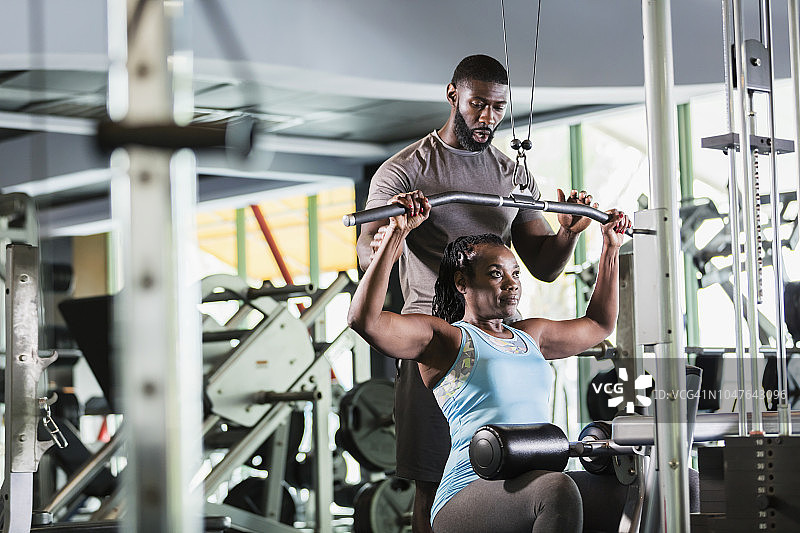 私人教练在健身房帮助中年妇女图片素材