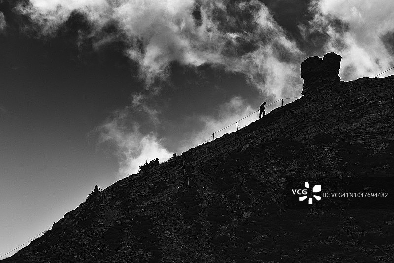 在铁索攀岩山峰上的登山者剪影图片素材
