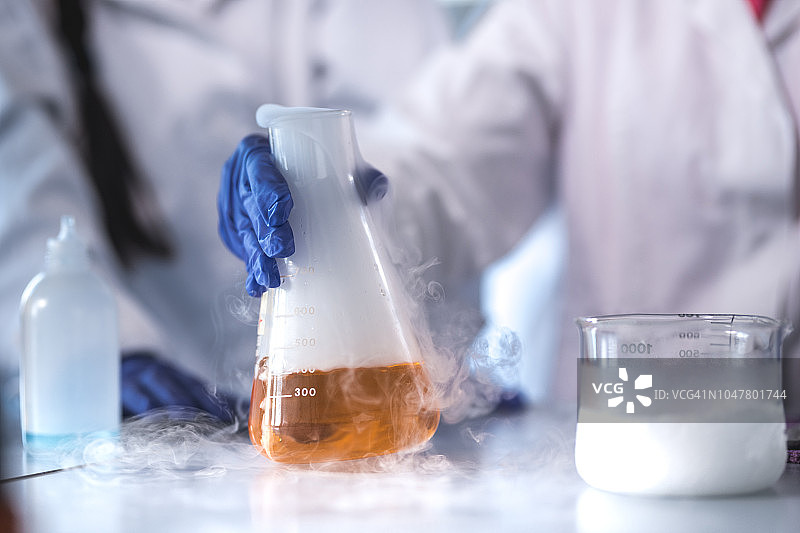 科学家手持装有蒸发液体的烧瓶图片素材