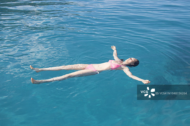 女人漂浮在太平洋热带岛屿的泻湖上图片素材