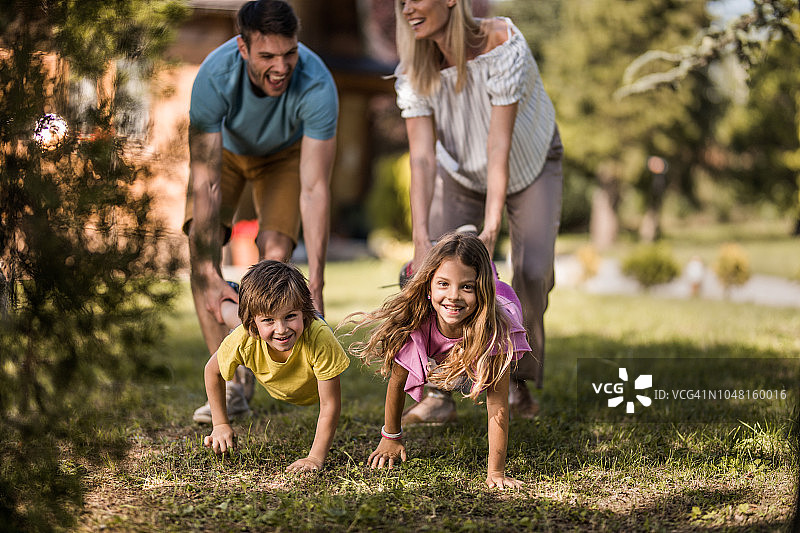 在后院玩独轮车比赛的快乐家庭图片素材