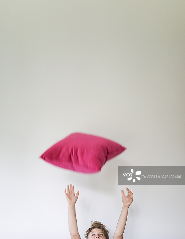 扔粉色枕头的男孩图片素材