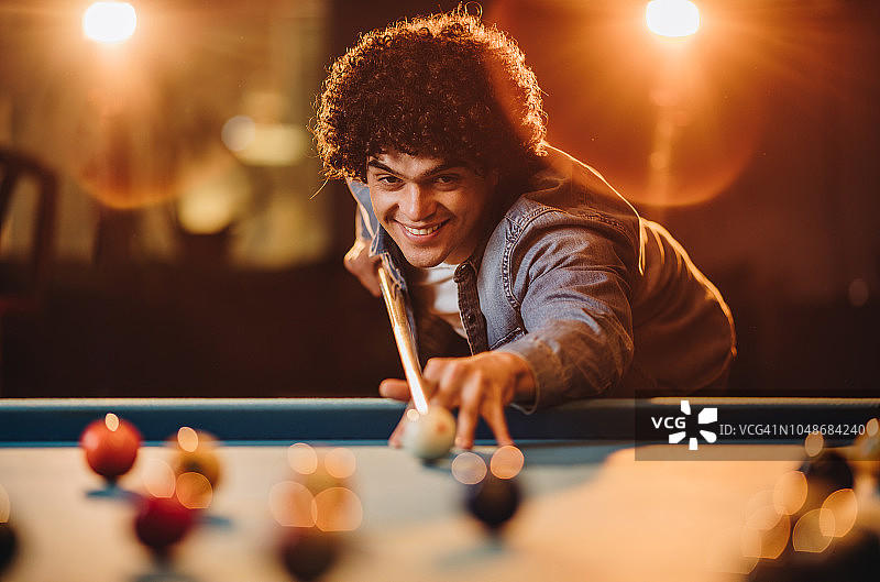 笑容满面的男人在娱乐俱乐部打斯诺克，瞄准球图片素材