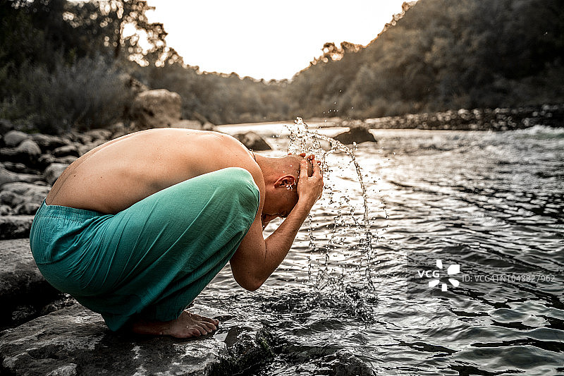 年轻男人在河岸边洗头图片素材