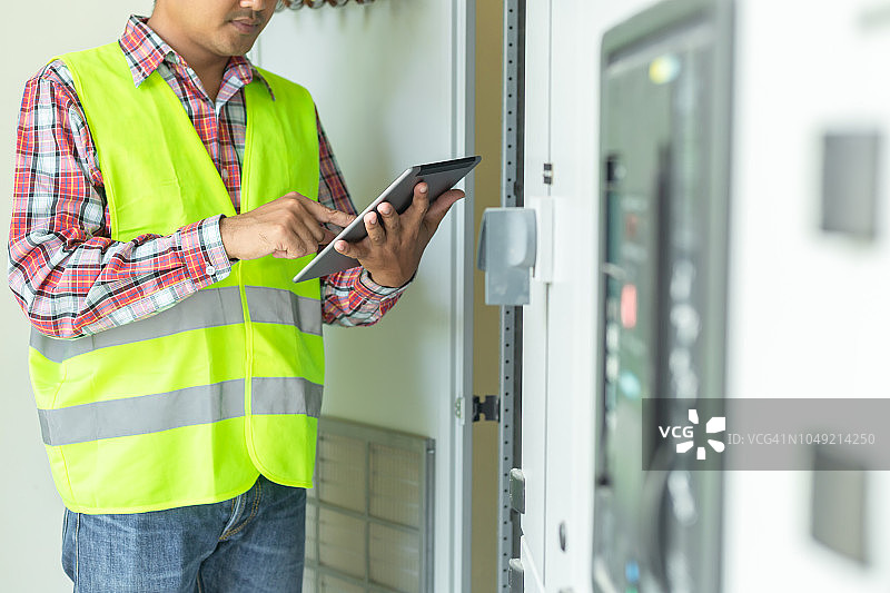 亚洲维修工程师用笔记本电脑检查继电保护系统。海湾控制单元，中压开关设备。图片素材