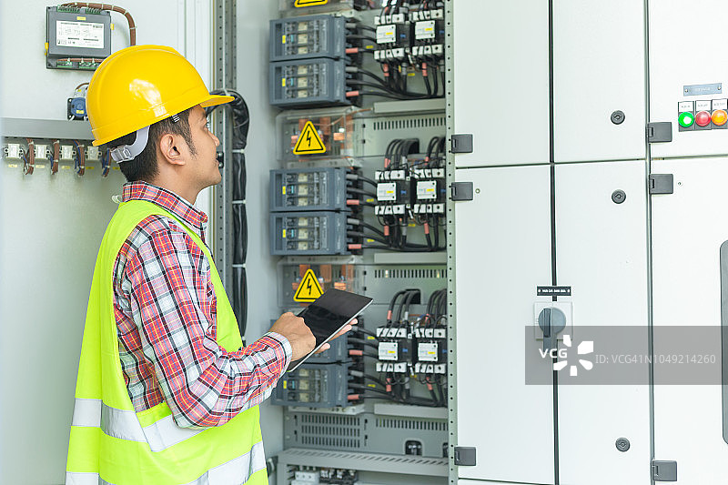亚洲维修工程师用笔记本电脑检查继电保护系统。海湾控制单元，中压开关设备。图片素材