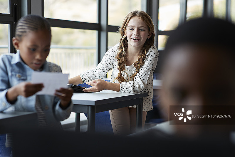 女孩看着纸条，同学在她身后偷看图片素材