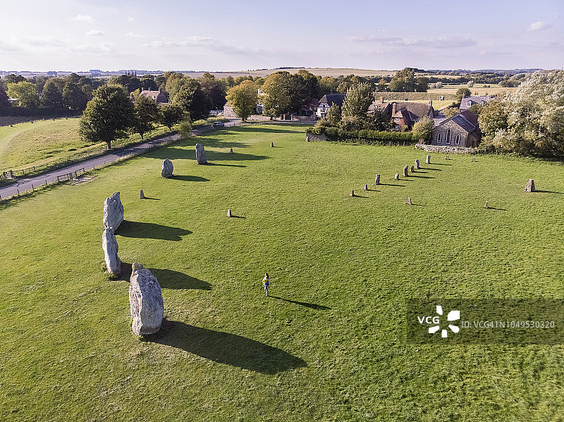 母亲抱着孩子站在田野上的巨石前图片素材