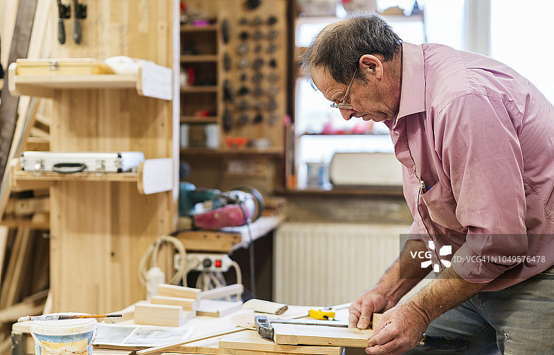 小型家具厂里，年长的木工用夹具组装木制零件图片素材