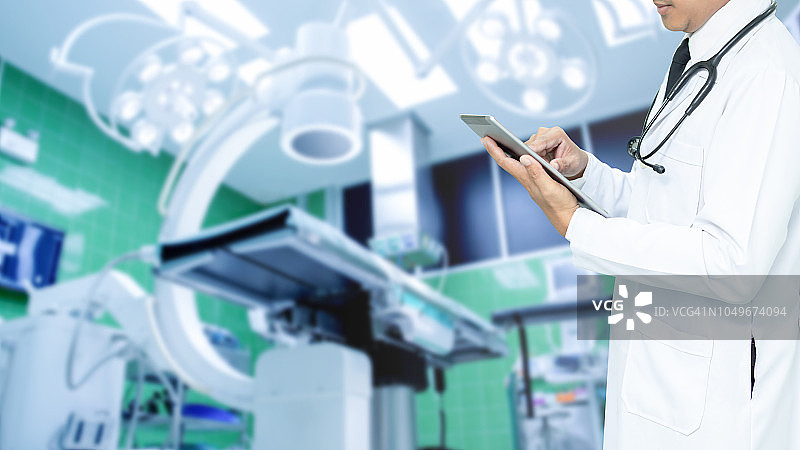 亚洲医疗保健，医生使用平板电脑，医院里带听诊器的男医生，配备现代化设备的手术室概念图片素材
