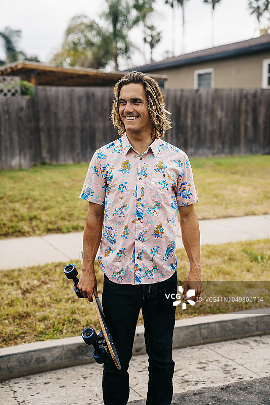 在郊区街道上手持滑板的年轻男子肖像图片素材