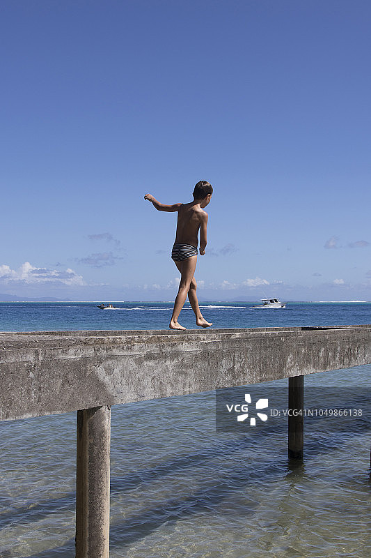孩子在波利尼西亚泻湖的碧蓝色海边的水泥浮桥上图片素材