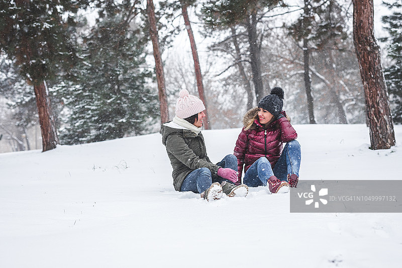 两位年轻女人坐在雪地上图片素材