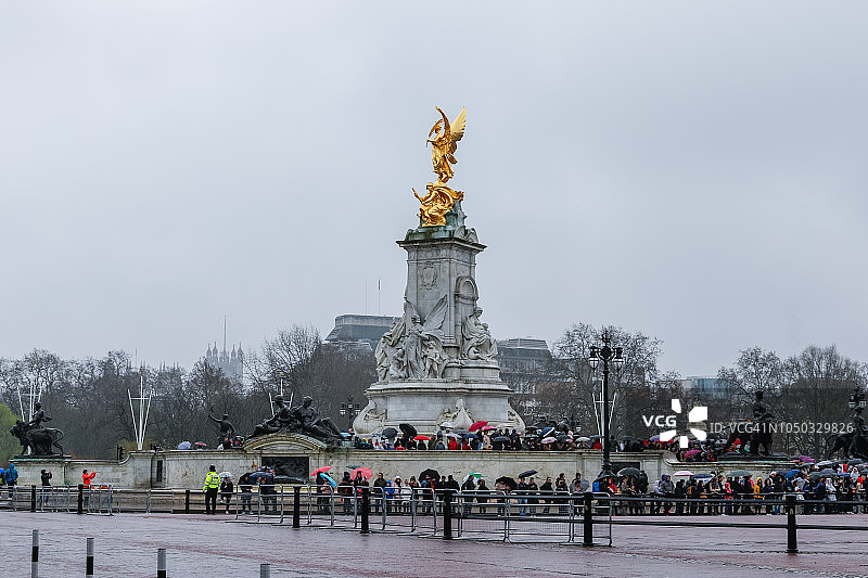 游客冒雨站在白金汉宫和维多利亚纪念碑前（伦敦，英格兰）图片素材