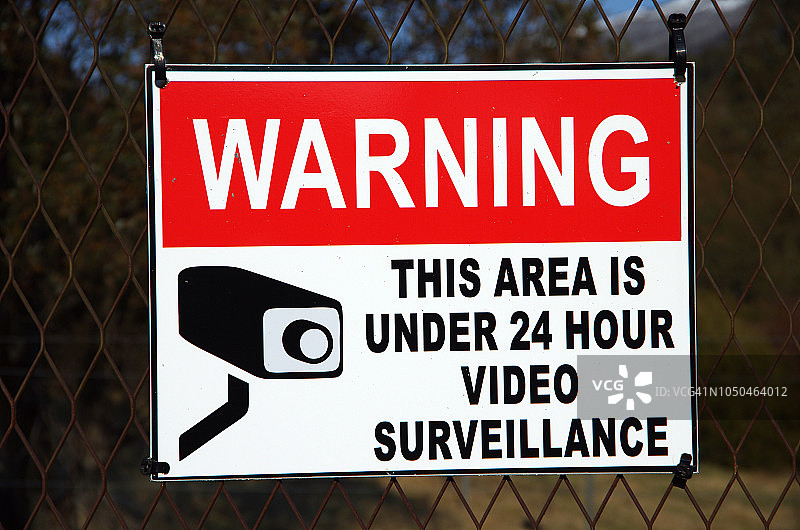 “警告：本区域受24小时视频监控”标志（铁丝网围栏）图片素材