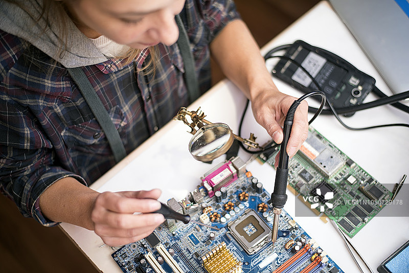 年轻女电子工程师焊接电脑主板图片素材