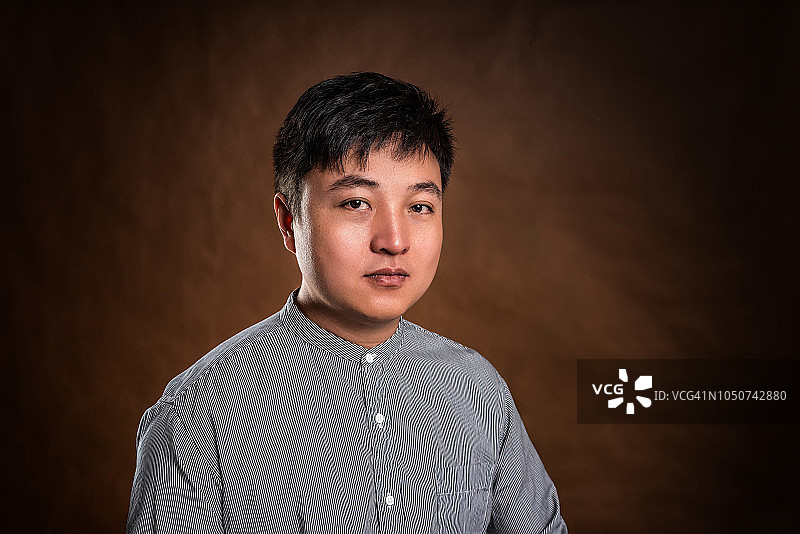 棕色背景下的自信年轻男商人肖像图片素材