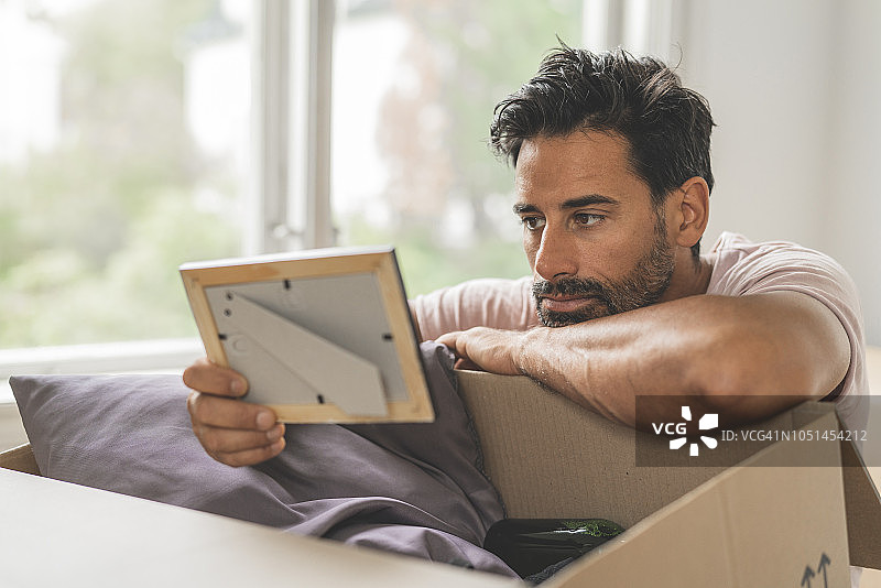 男子搬进新家时翻看旧照片图片素材