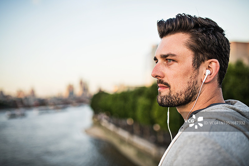 年轻男人戴耳机站在桥上听音乐图片素材
