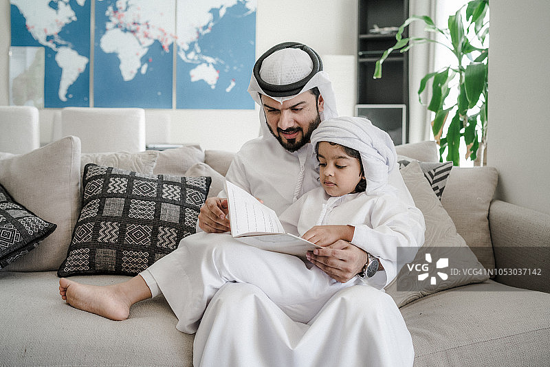 阿拉伯父亲和儿子在家阅读书籍做功课图片素材