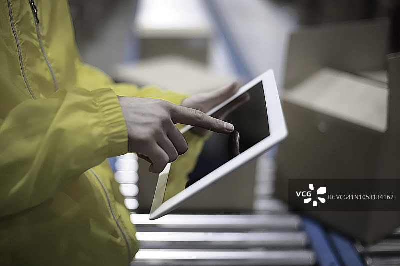 仓库工人使用数字平板电脑在传送带上图片素材