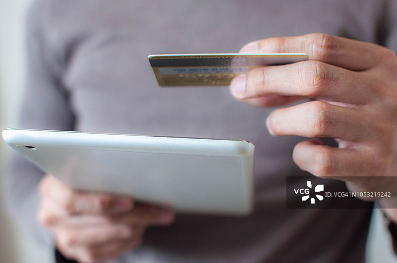 一位年轻人正在使用信用卡从平板电脑上购买商品图片素材