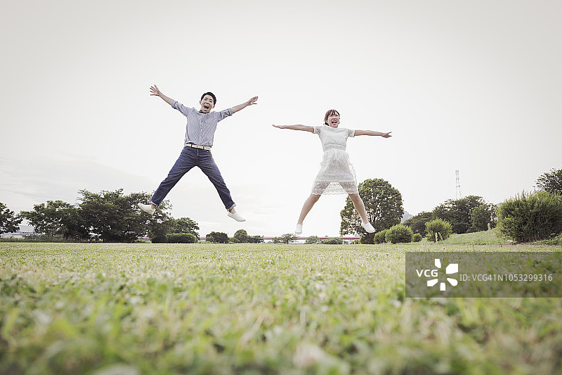 情侣在绿色田野里一起跳跃图片素材