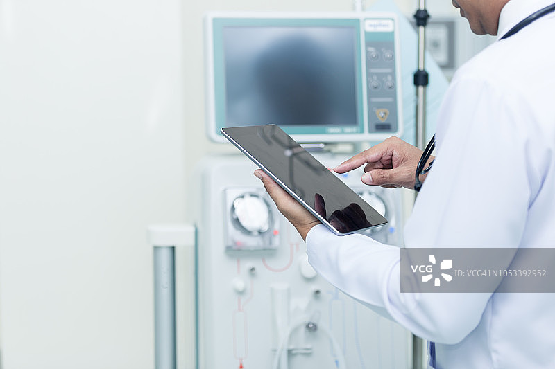 医疗护理：年轻医生使用平板电脑检查透析设备图片素材