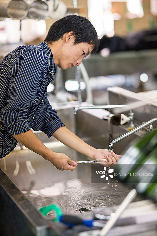 中年男人在小型精酿啤酒厂清洗啤酒酿造设备图片素材