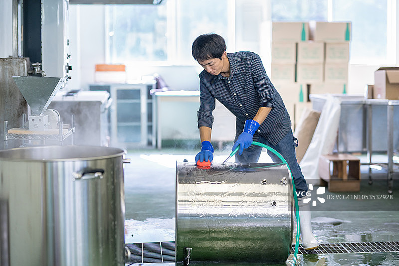 中年男人在小型精酿啤酒厂清洗啤酒酿造设备图片素材
