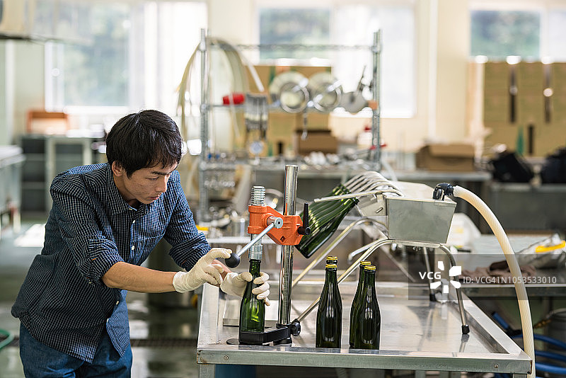 酿酒师在小批量精酿啤酒厂里装瓶他的产品图片素材
