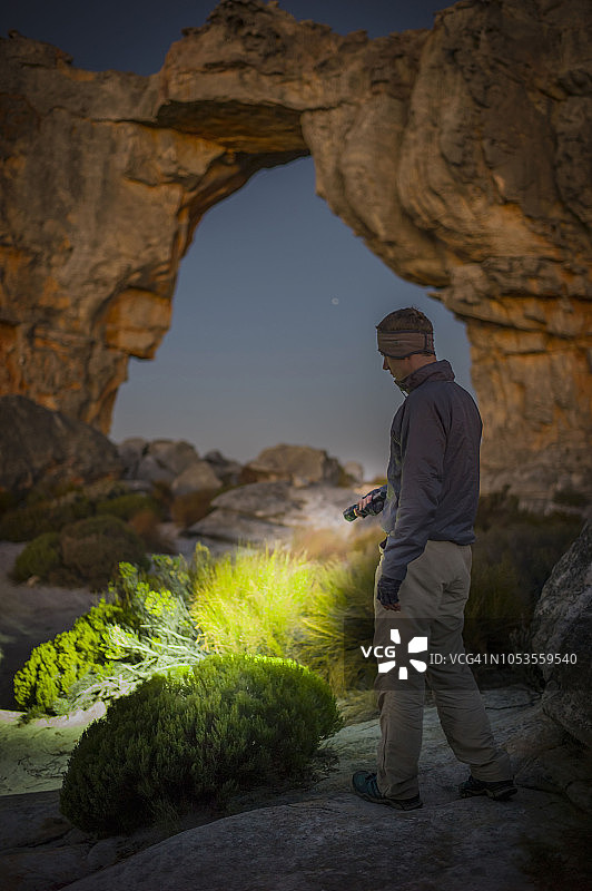 男人在南非西开普省锡德伯格荒野区的沃尔夫伯格拱门营地用手电筒探险图片素材
